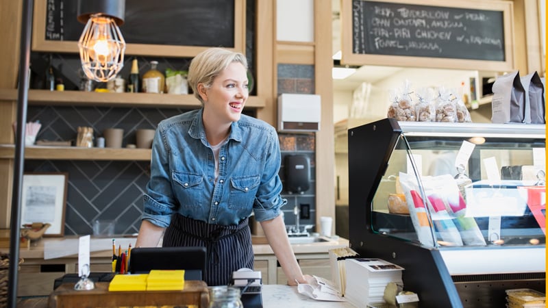 Retailer behind front counter in her shop.