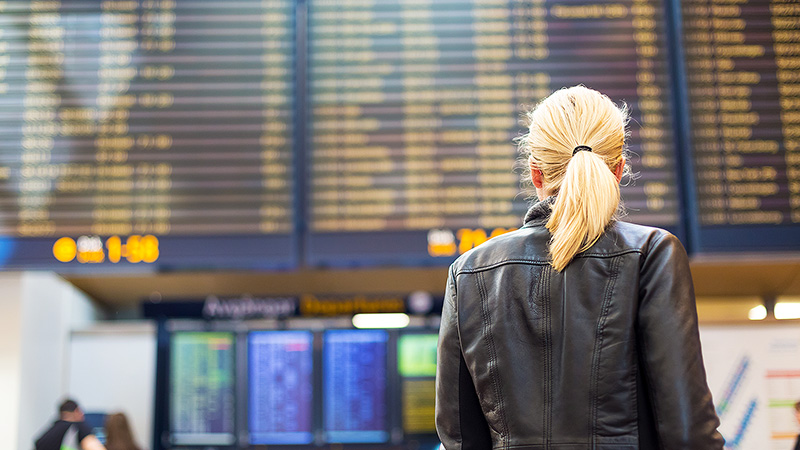 Woman at an airport looking up at the flight timetable. Woman at an airport looking up at the flight timetable.