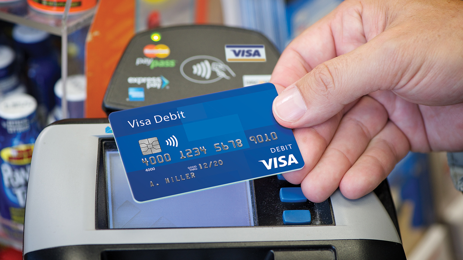 cashier-paywave-1600x900 Person using a Visa payWave debit card at a payment terminal.