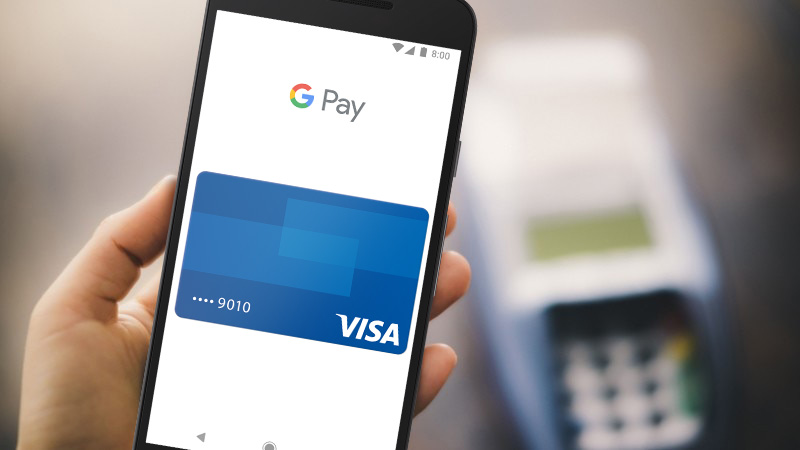 Hand holding a mobile phone with Google Pay Visa card shown on the screen. Hand holding a mobile phone with Google Pay Visa card shown on the screen.