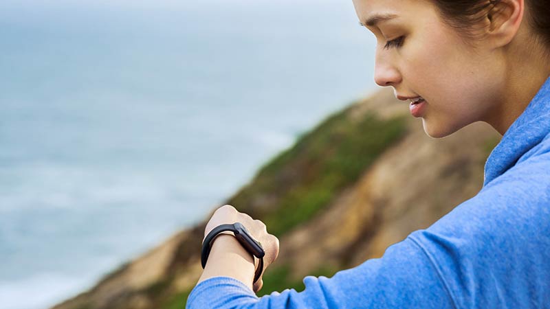 Woman checking her watch on top of a cliff overlooking the ocean. Woman checking her watch on top of a cliff overlooking the ocean.